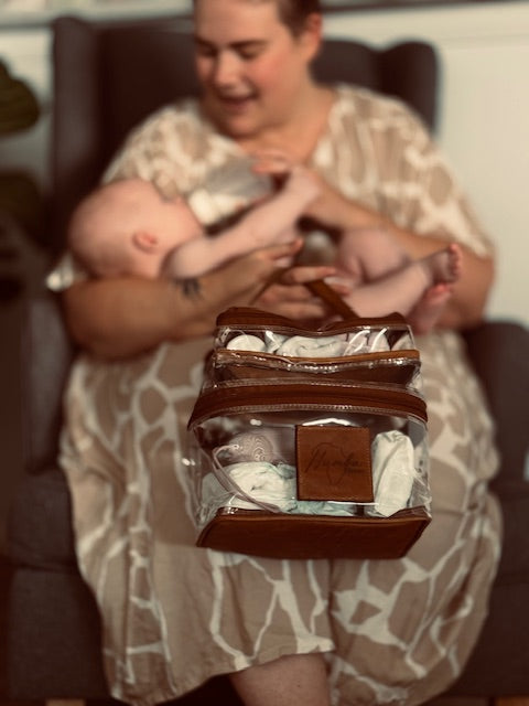 Woman holding a baby and a Humba Hides All-Purpose Bag – Multi-Use Organiser - Medi Bag with baby items inside.