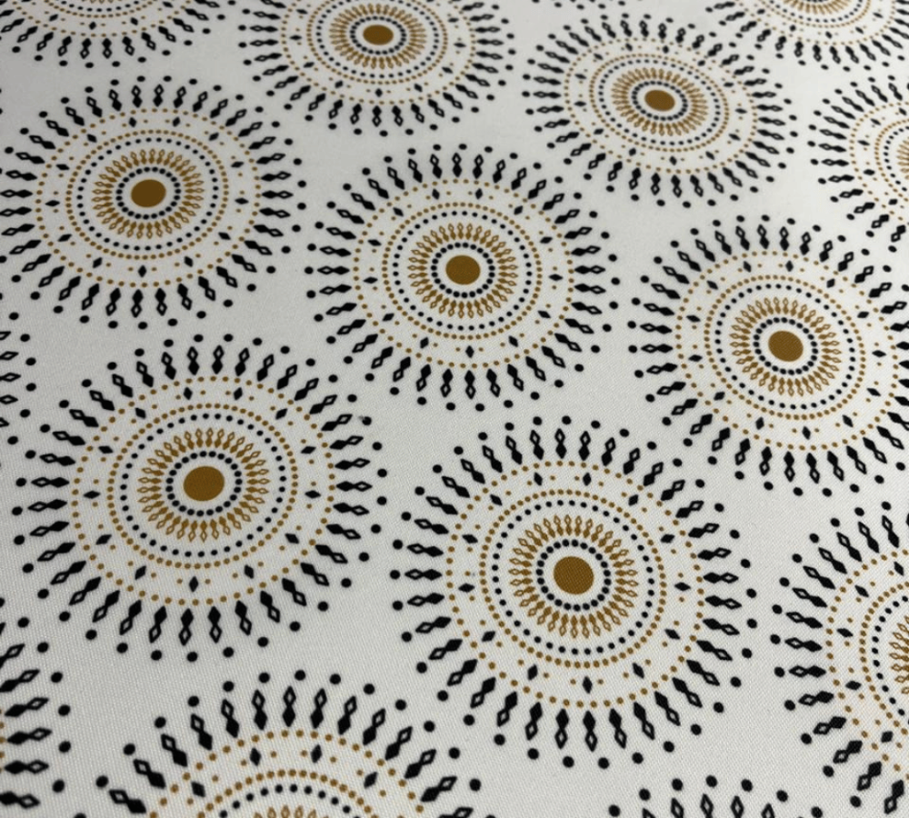 Patterned fabric with circular designs in black, brown, and beige on a white background